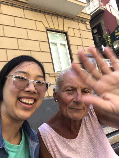 Melbourne Tang taking a selfie with local 'nonna' saying hi with her blurred hand, indicating she's saying hello at the side of her face