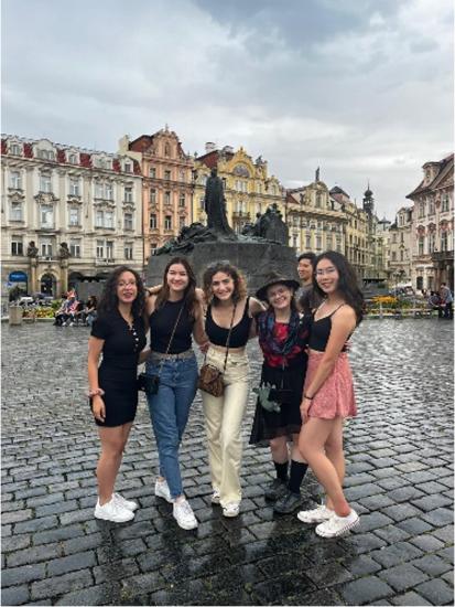 Willow Huang standing far right with 5 others pictured in a plaza in Germany with a large grey statue 