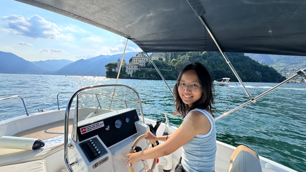 Lily Sun looking to her side as she steers a boat out on sea in Italy