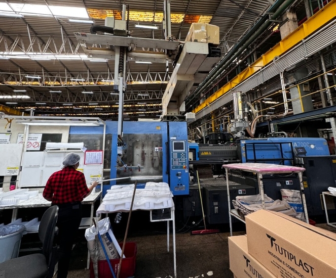 A factory with heavy machinery and boxes to the right with the TUTIPLAST logo