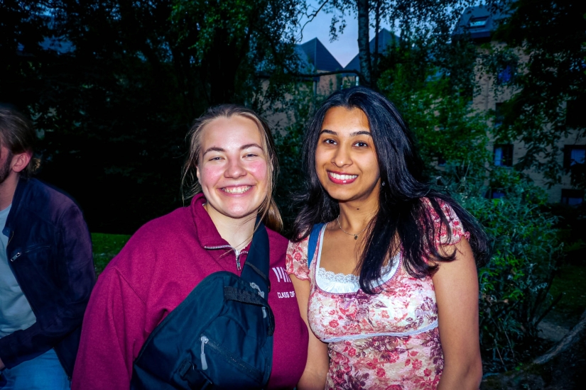 A flash on Zaee with another MISTI student with the grass and some trees in the background 