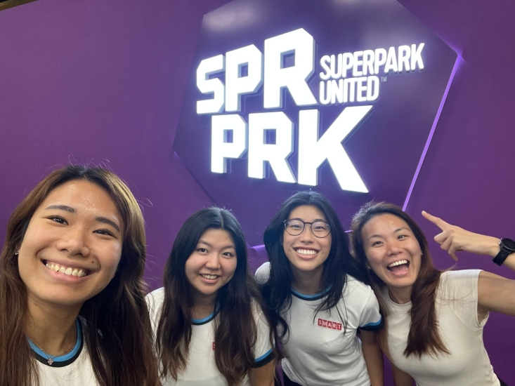 A selfie of Sidney and three others in front of a purple wall with a sign "SPR PRL Superpark United"