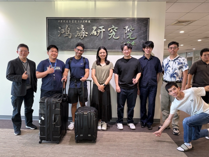 Kumail, pictured third from the left, with 7 other people standing in front of a white wall with a dark grey plaque with chinese words