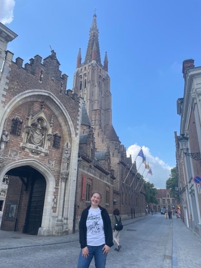 Emilia pictured with the Church of Our Lady in Bruges, Belgium on a sunny day