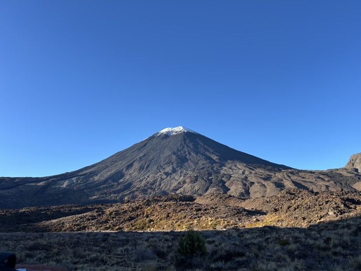 A mountain with a snowcap top and blue skies