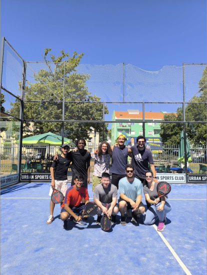 Paulo Henrique squatting on the far left with 8 other work colleagues on a tennis court on a sunny day
