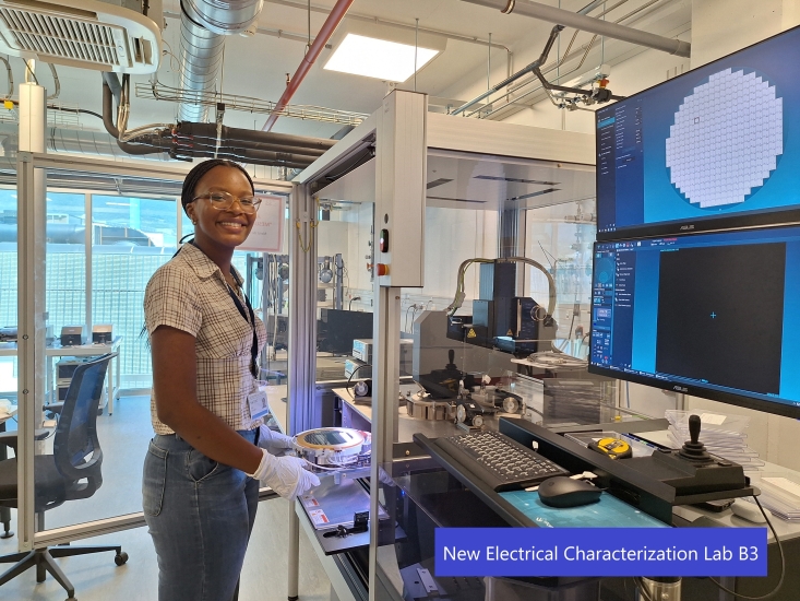 Zuri Vallery in white gloves holding onto a metal bowl that is heading into a machinery in a lab