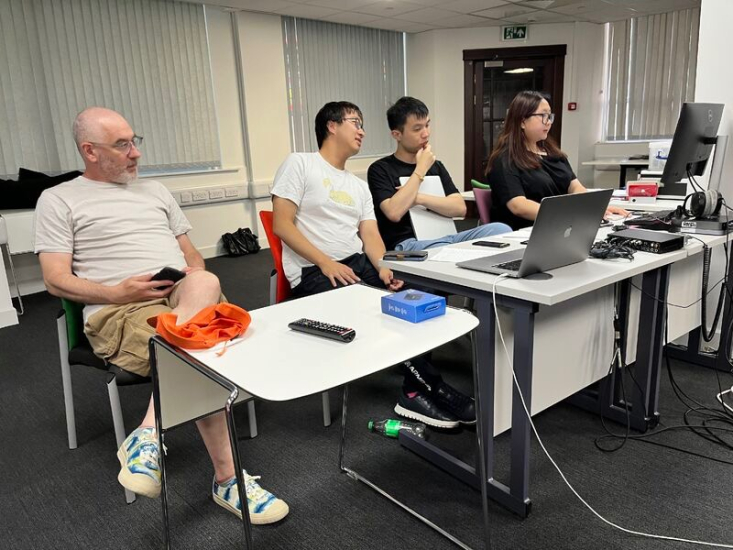 Elaine Chang looking at a monitor while seated with three colleagues in a row